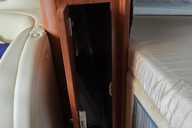 Slide: The Image of 2007 Rinker 320 Express Cruiser interior with open wooden cabinet and cushioned seating. - 24