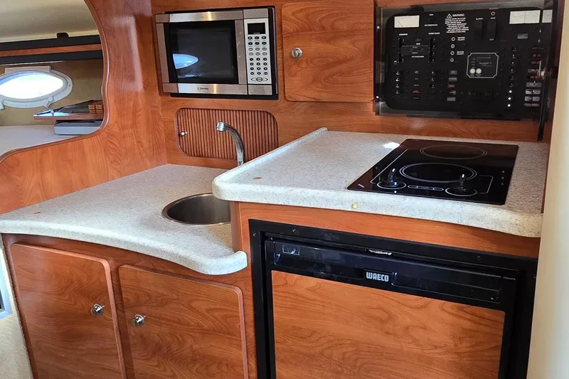 Slide: The Image of 2007 Rinker 320 Express Cruiser kitchen with microwave, sink, stove, and compact fridge. - 25
