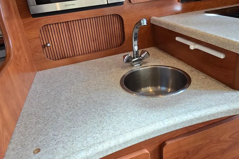 Slide: The Image of 2007 Rinker 320 Express Cruiser kitchen with sink and wooden cabinetry. - 26