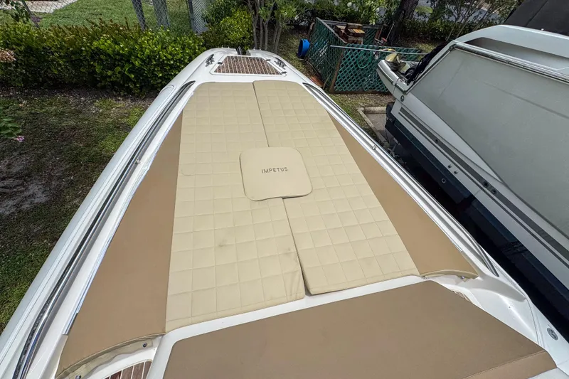 Slide: The Image of 2023 Tender Impertus 36 boat with beige cushioned deck, parked outdoors. - 11