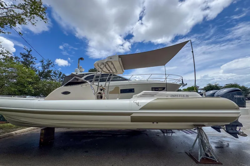 Slide: The Image of 2023 Tender Impertus 36 boat with canopy, parked outdoors under a blue sky. - 4