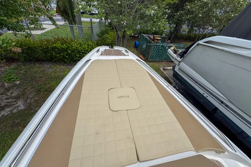 Slide: The Image of 2023 Tender Impertus 36 boat deck with tan cushioned seating, surrounded by greenery. - 43