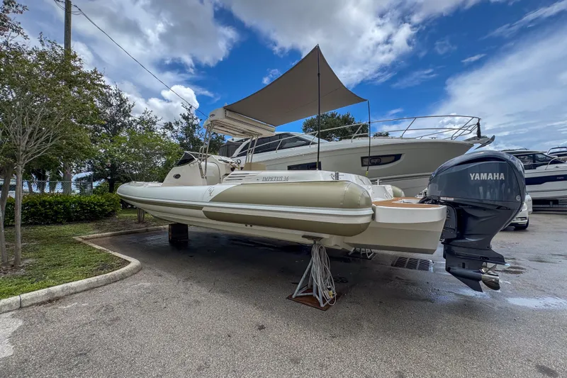 Slide: The Image of 2023 Tender Impertus 36 boat with Yamaha engine, parked outdoors under a canopy. - 6