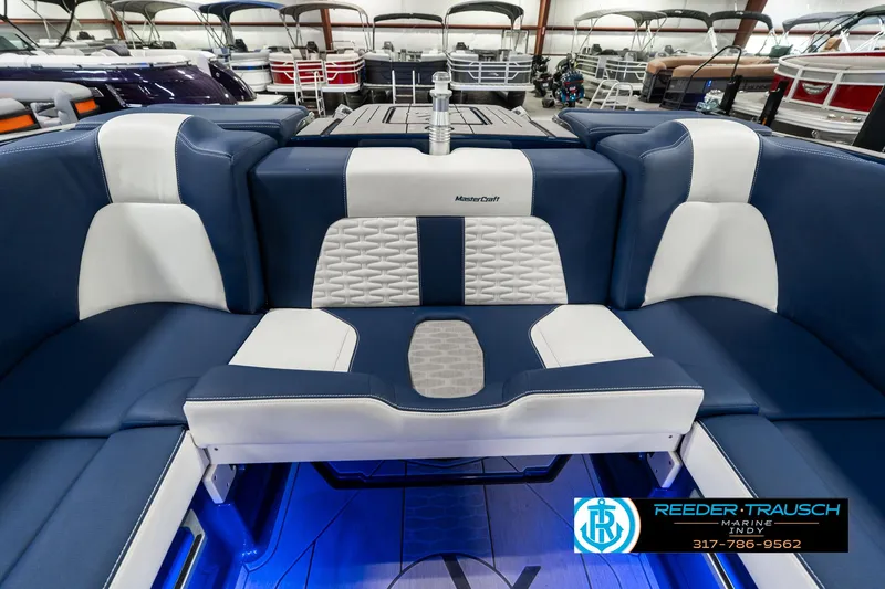 Slide: The Image of 2025 MasterCraft X24 boat interior with blue and white seating, showcased in a showroom. - 21