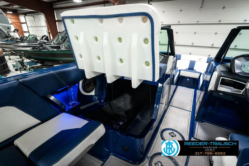 Slide: The Image of 2025 MasterCraft X24 boat interior with blue and white seating, open storage compartment. - 27