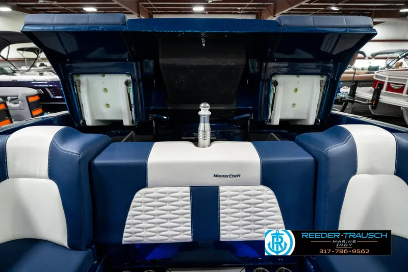 Slide: The Image of 2025 MasterCraft X24 boat interior with blue and white seating, open storage compartments. - 35