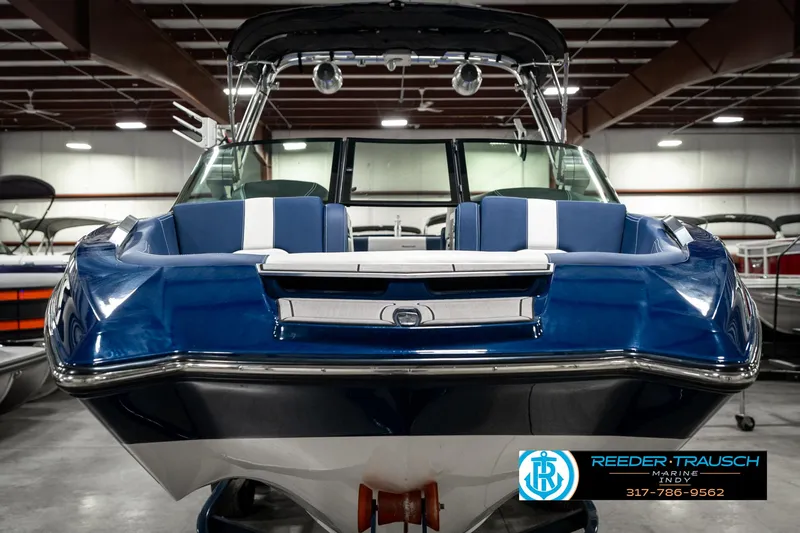 Slide: The Image of 2025 MasterCraft X24 boat in showroom, blue and white design, front view. - 5