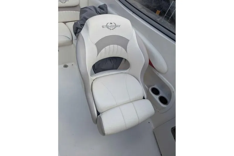 Slide: The Image of 2013 Stingray 225cr boat seat with white and gray upholstery, featuring cup holders. - 16
