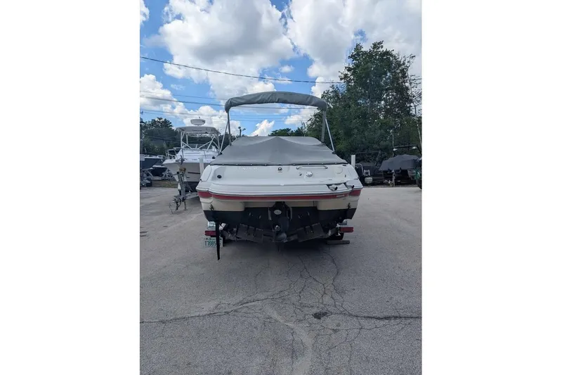 Slide: The Image of 2013 Stingray 225cr boat, rear view, parked outdoors under a cloudy sky. - 3