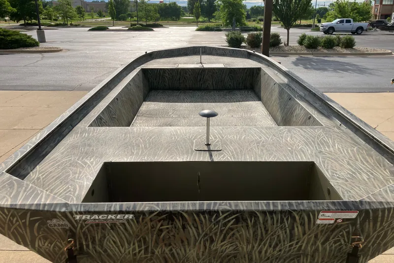 Slide: The Image of 2026 Tracker Grizzly 1860 Utility boat with camouflage design in a parking lot. - 2