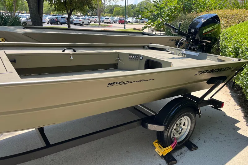 Slide: The Image of 2026 Tracker Grizzly 1654 T Sportsman boat on trailer, parked outdoors. - 2