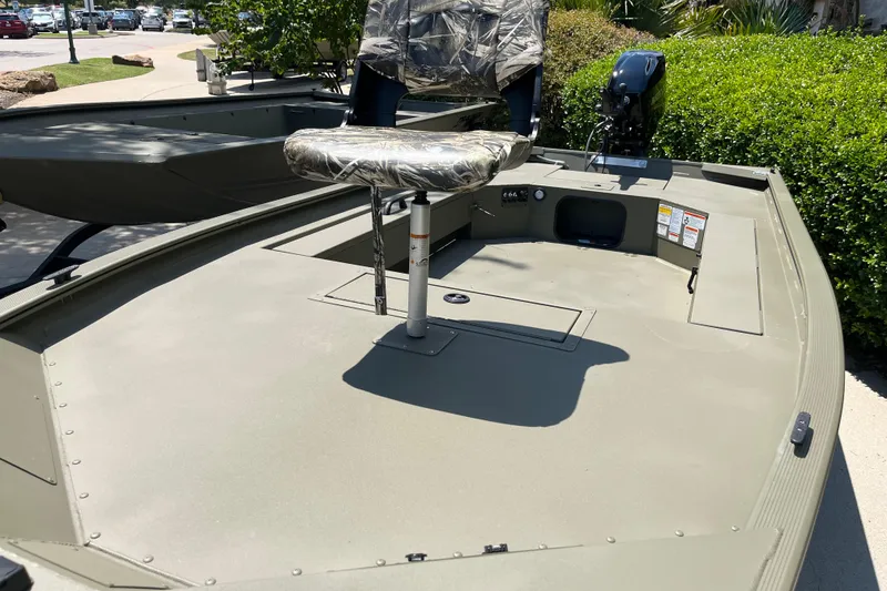 Slide: The Image of 2026 Tracker Grizzly 1654 T Sportsman boat with camo seat and motor, parked outdoors. - 4