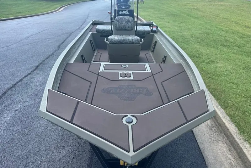 Slide: The Image of 2026 Tracker Grizzly 1860 CC boat on pavement, featuring spacious deck and seating. - 2