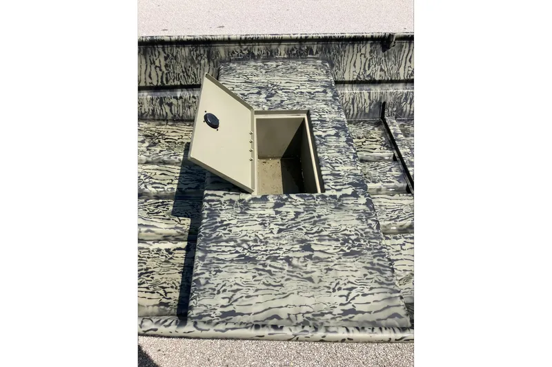 Slide: The Image of 2026 Tracker Grizzly 15 Jon boat with open storage compartment, featuring camouflage design. - 6