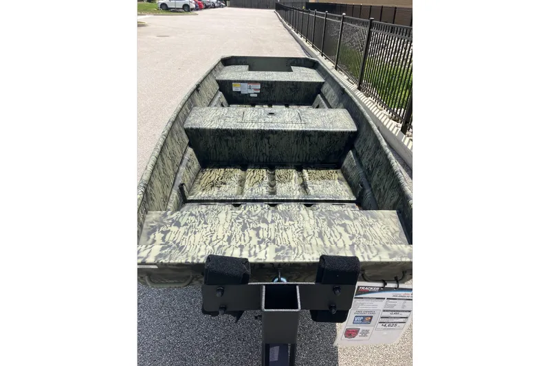 Slide: The Image of 2026 Tracker Grizzly 15 Jon boat with camouflage design, parked on pavement. - 4