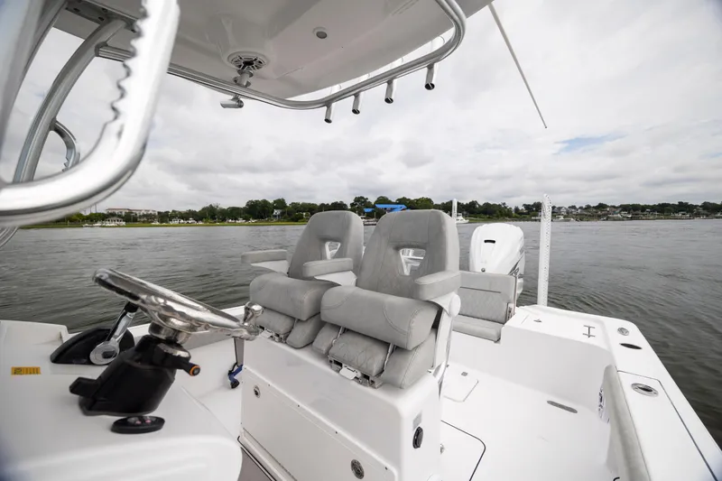Slide: The Image of 2020 Sportsman Masters 267OE Bay Boat interior with dual seats and steering wheel on water. - 13