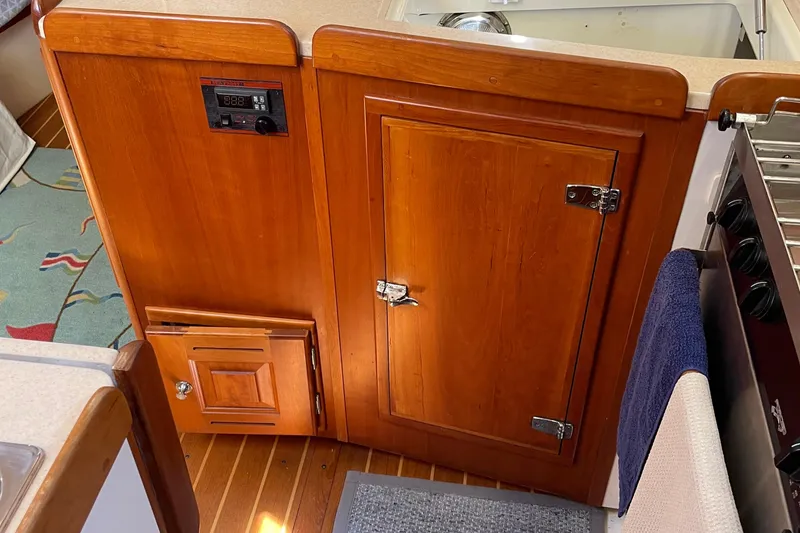 Slide: The Image of Wooden cabinetry in a 2004 Tartan 3700 yacht kitchen, featuring a control panel and towel. - 23
