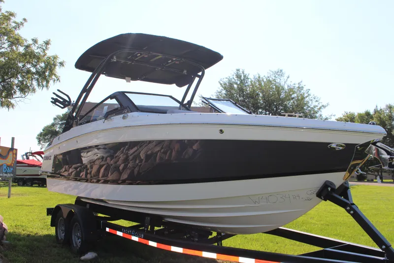 Slide: The Image of 2025 Cobalt R4 Surf boat on trailer, parked on grass under clear sky. - 12