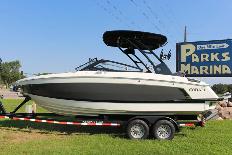 Slide: The Image of 2025 Cobalt R4 Surf boat on trailer at Parks Marina, under clear blue sky. - 16