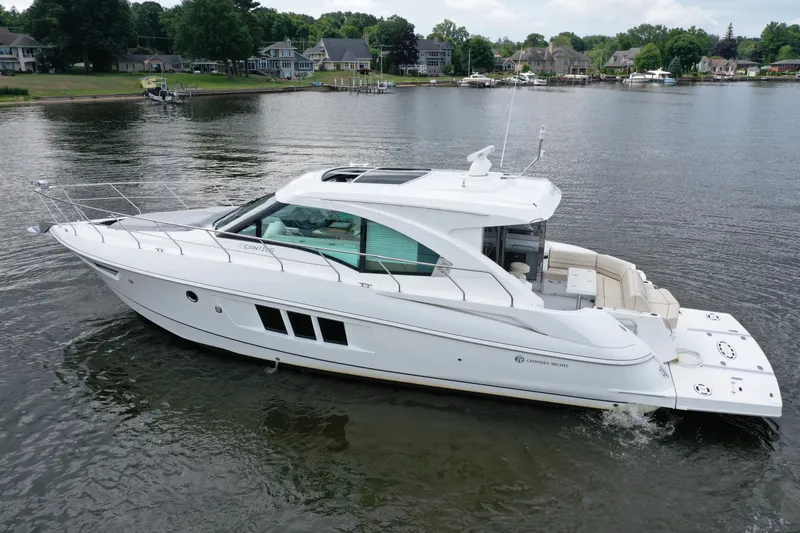 Slide: The Image of 2017 Cruisers Yachts 45 Cantius on a serene lake with waterfront homes. - 1