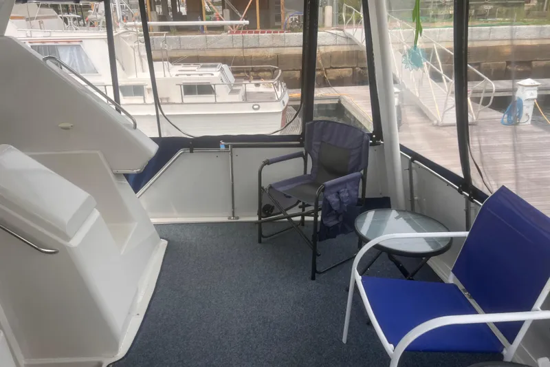 Slide: The Image of 1994 Carver 350 yacht interior with blue chairs and glass table, docked at marina. - 26