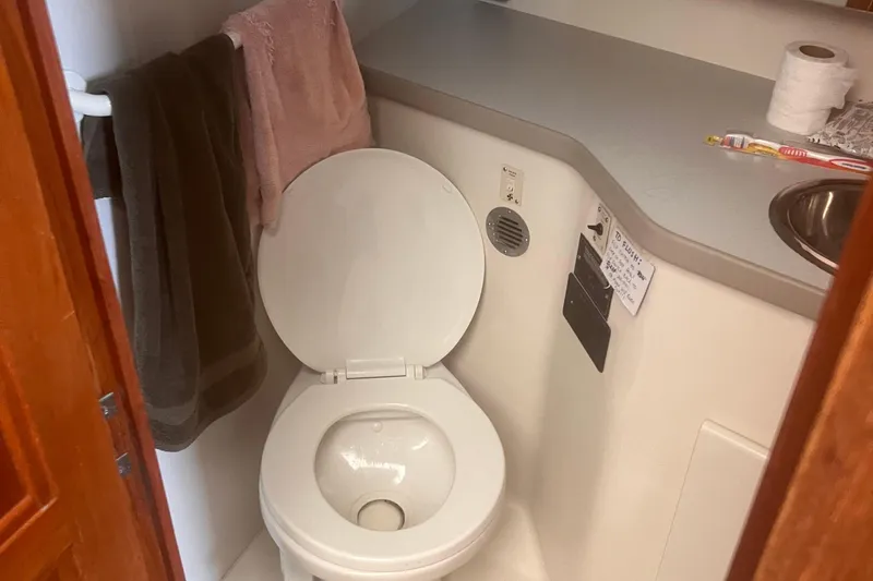 Slide: The Image of 1994 Carver 350 boat bathroom with toilet, towels, and sink area. - 44