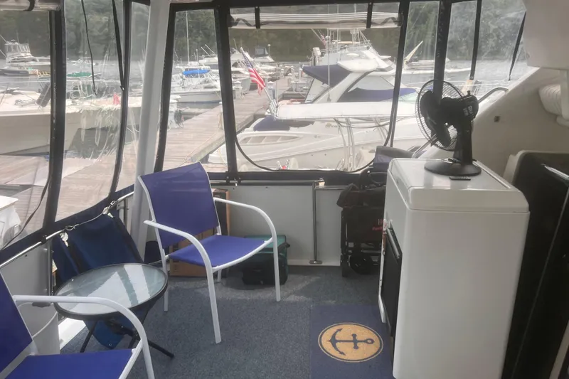 Slide: The Image of Interior of a 1994 Carver 350 yacht with marina view, featuring chairs and a fan. - 25