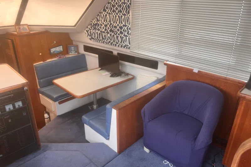 Slide: The Image of 1994 Carver 350 yacht interior with dining area, blue seating, and a cozy armchair. - 31
