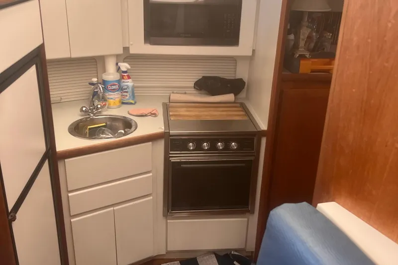 Slide: The Image of Compact kitchen in a 1994 Carver 350 boat with sink, stove, and cleaning supplies. - 34