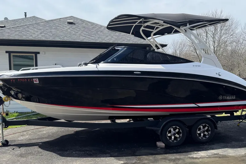 Slide: The Image of 2020 Yamaha Boats 242SE on trailer, black and white design, parked outdoors. - 0