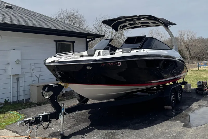 Slide: The Image of 2020 Yamaha Boats 242SE on trailer, parked beside a white building. - 1