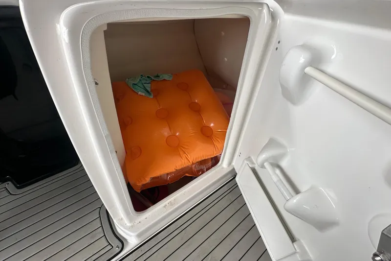 Slide: The Image of Storage compartment in 2020 Yamaha Boats 242SE with orange inflatable cushion. - 30