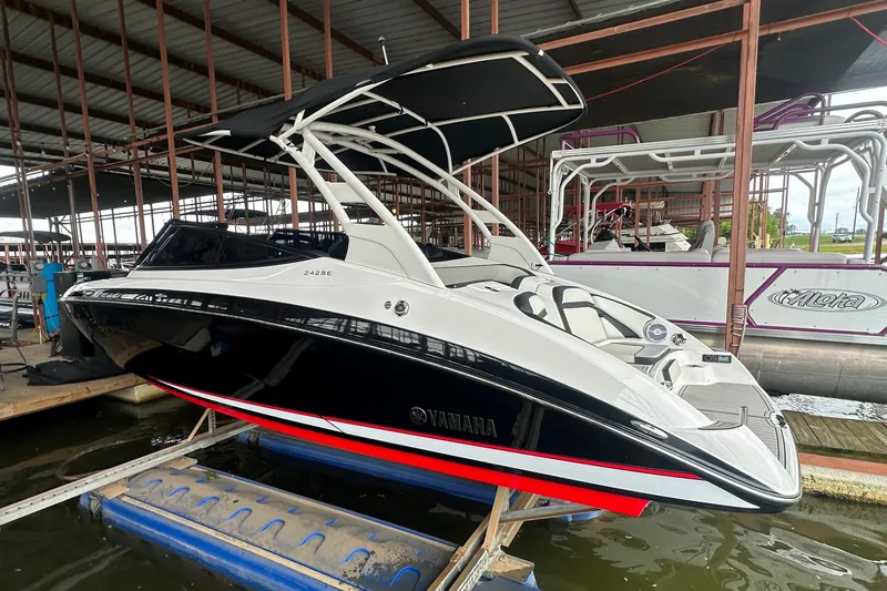 Slide: The Image of 2020 Yamaha Boats 242SE in a marina, sleek black and white design, under a covered dock. - 7