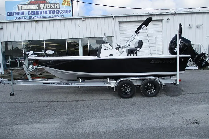 Slide: The Image of 2026 Sea Pro 210 Bay boat on trailer, parked outside a truck wash facility. - 5