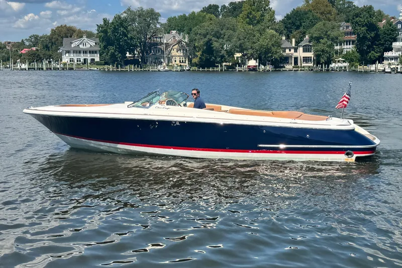 Slide: The Image of 2008 Chris-Craft Launch 28 boat cruising on a scenic lake with waterfront homes. - 10