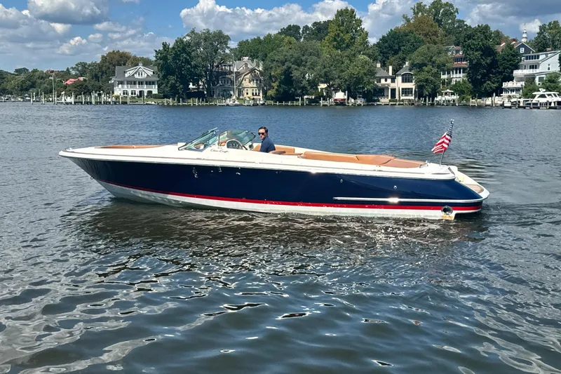 Slide: The Image of 2008 Chris-Craft Launch 28 boat cruising on a scenic lake with waterfront homes. - 12