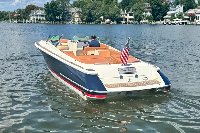 Slide: The Image of 2008 Chris-Craft Launch 28 boat cruising on a scenic lake with American flag. - 14