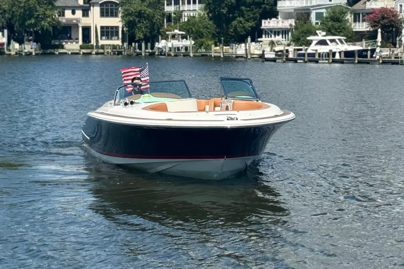 Slide: The Image of 2008 Chris-Craft Launch 28 boat on a serene waterfront with American flag. - 5