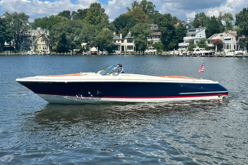 Slide: The Image of 2008 Chris-Craft Launch 28 boat on a serene lake with waterfront homes. - 8