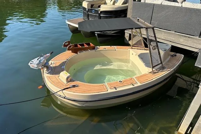 Slide: The Image of 2022 Spacruzzi V-1 boat with hot tub, docked on a sunny day. - 1