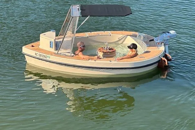 Slide: The Image of Floating hot tub boat, Spacruzzi V-1, 2022 model, with two people relaxing on water. - 3