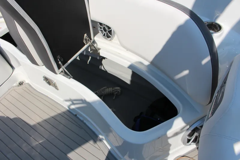 Slide: The Image of 2023 Crownline E285 boat interior storage compartment with open seat and visible rope. - 15
