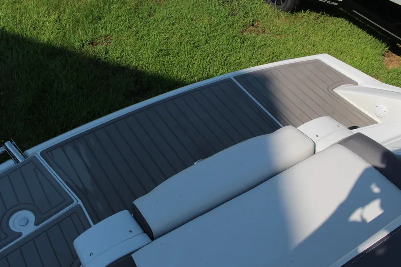 Slide: The Image of 2023 Crownline E285 boat deck with cushioned seating on grass. - 19