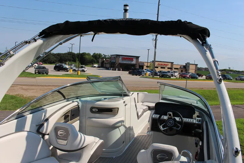 Slide: The Image of 2023 Crownline E285 boat interior with steering wheel and seating, parked near a shopping area. - 21