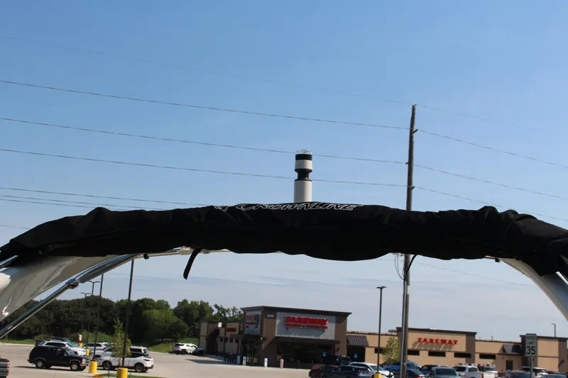 Slide: The Image of 2023 Crownline E285 boat with covered top, parked near a shopping area. - 22