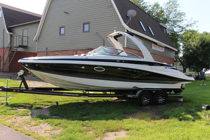 Slide: The Image of 2023 Crownline E285 boat on trailer, parked near a building. - 25