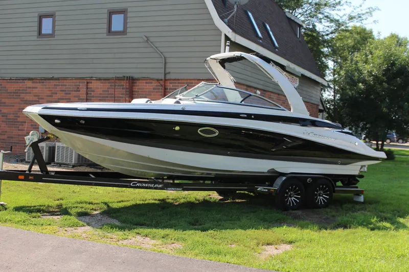 Slide: The Image of 2023 Crownline E285 boat on trailer, parked near a brick building. - 26