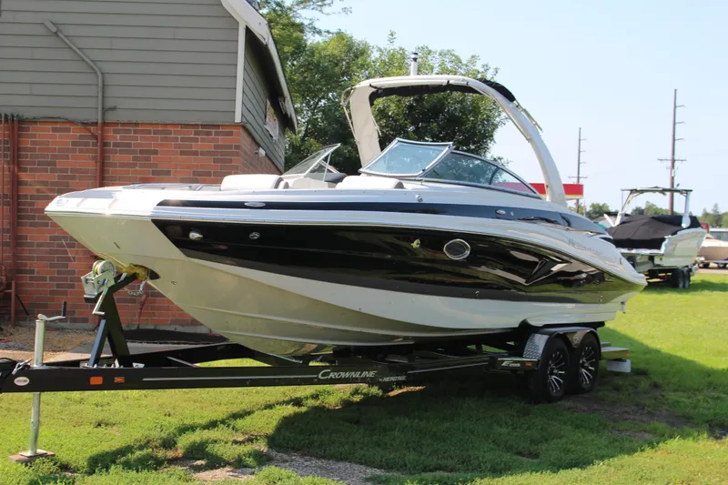 Slide: The Image of 2023 Crownline E285 boat on trailer, parked outdoors near a brick building. - 27