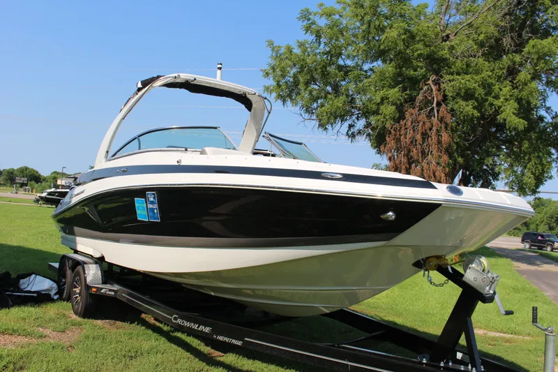 Slide: The Image of 2023 Crownline E285 boat on trailer, parked on grass under clear blue sky. - 29