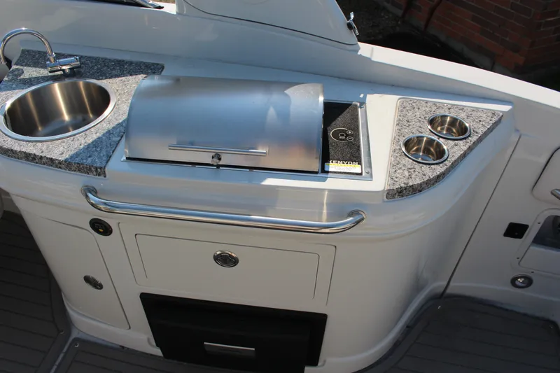 Slide: The Image of 2023 Crownline E285 boat kitchenette with sink, grill, and cup holders. - 37
